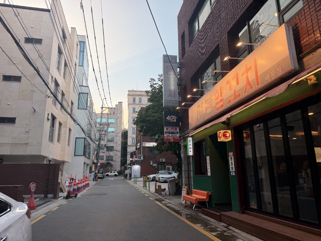 Evening alley between Korean villa buildings with lit shop signs